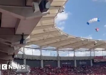Moment parachutist left dangling on stadium roof