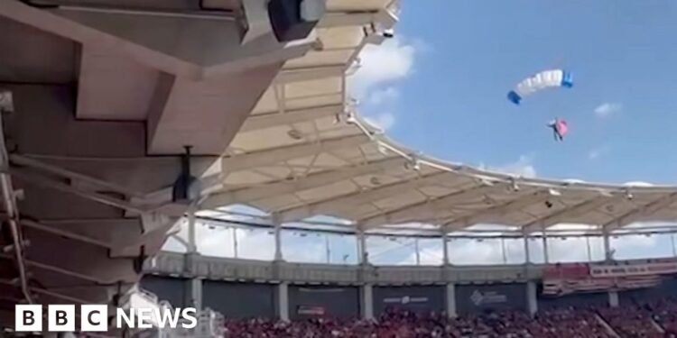 Moment parachutist left dangling on stadium roof
